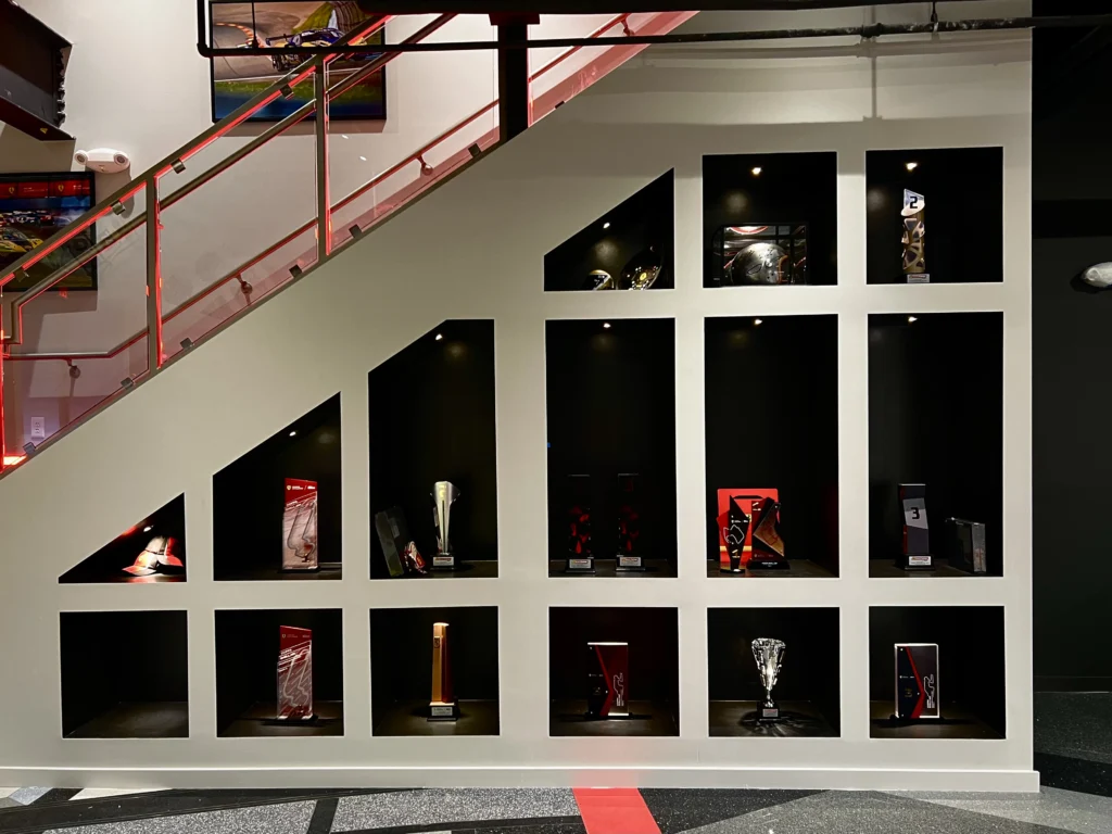 Precision lighting design highlighting a trophy case filled with automotive memorabilia in a high-end car cave in Greensboro.