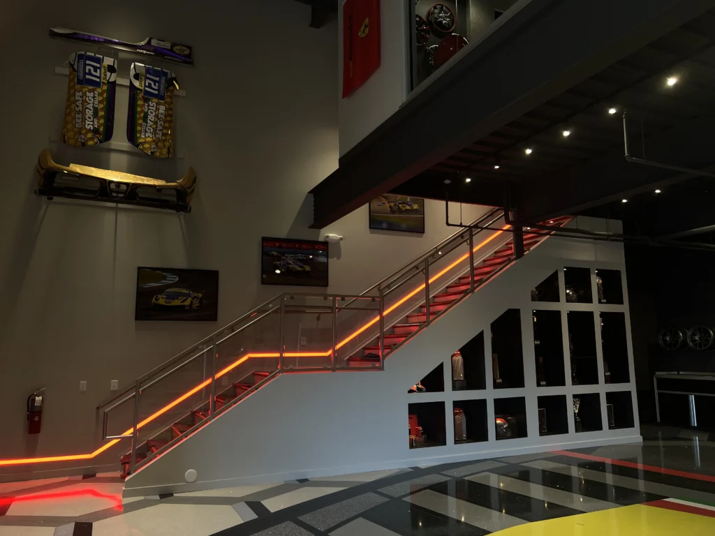 Soft white LED step lighting installed along a modern staircase in a luxury car cave, enhancing safety and ambiance.