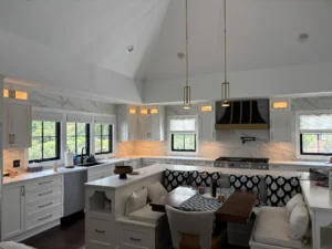 Bright kitchen with pendant lights over a banquette and marble backsplash.