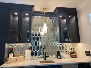 Modern wet bar with mirrored backsplash and illuminated cabinets.