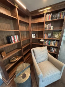 arm wooden bookshelves and a comfortable chair in a cozy reading nook.