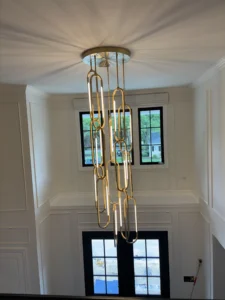 Elegant chain-link chandelier illuminating a spacious foyer with windows.